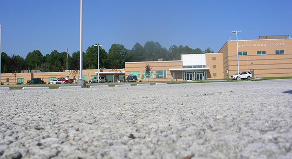 Photo of Milton Middle School porous concrete parking lot. The school is in the background with a close up of the concrete in the foreground.