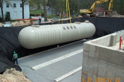 New underground storage tank being lowered into position by a crane