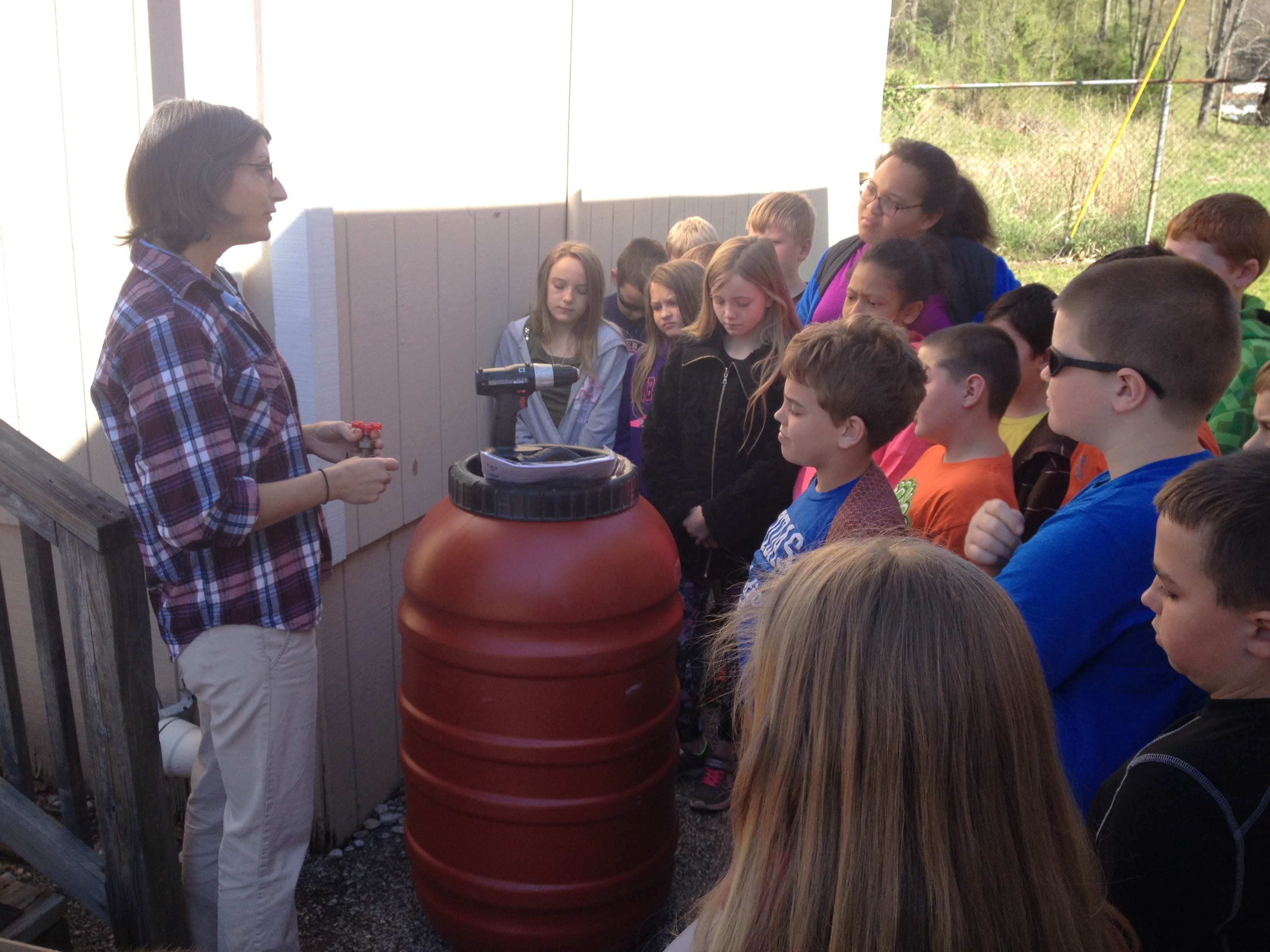 Tomi Bergstorm demonstrates how to build a rain barrel to a group of students.