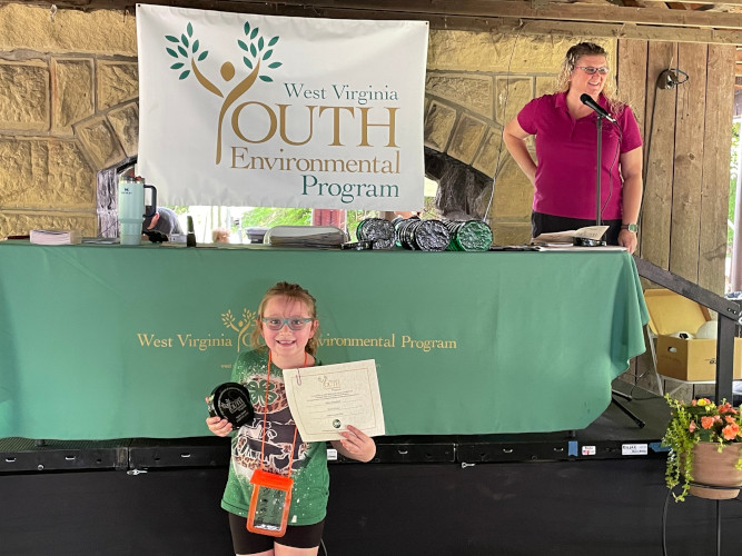 A member of the Hobos Cloverbuds 4-H group poses for a photo while holding a glass award and certificate.