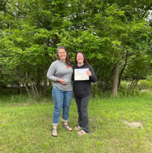 A member of Appalachian Expeditions, from Tucker County, holds up a glass award, standing alongside Beth Henry-Vance of the DEP's Youth Environmental Program.