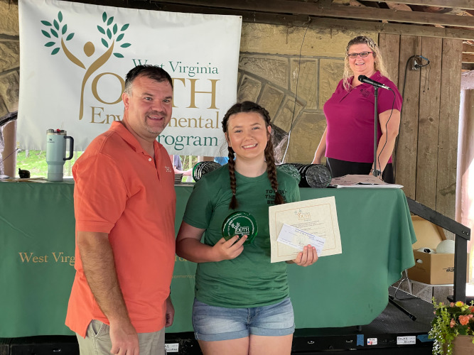 Kierstyn Hart, of the Letart Pioneers 4-H Club of Mason County, holds up her glass award, certificate and check for picture, alongside A.J. Hoskins.